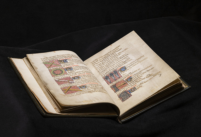 A bound Medieval manuscript open to a page of text illustrated with objects relating to the Passion of Christ