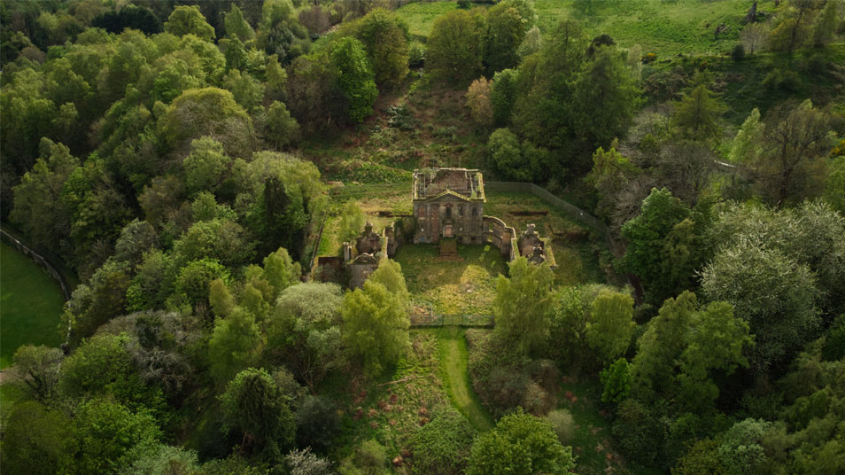 Mavisbank House aerial view showing the house in state of disrepair and surrounded by trees and greenery. 