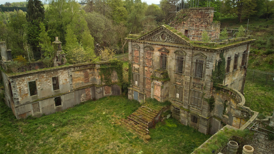 A side view of Mavisbank House showing trees, grass and other plants growing over the walls, steps and through the roof