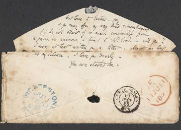 An envelope with the lines of text written on the flap and postmarks on the front