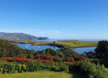 View across the Isle of Canna showing blue sky, hills in the distance and sailboats on the water