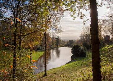 The gardens at Hestercombe looking out over a lake surrounded by trees and grass. 