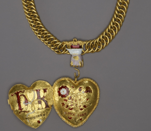 Close up view of the necklace. Showing detail of chain with hand shaped clasp coming from a cloud and the heart-shaped pendant with enamel decoration shown open.